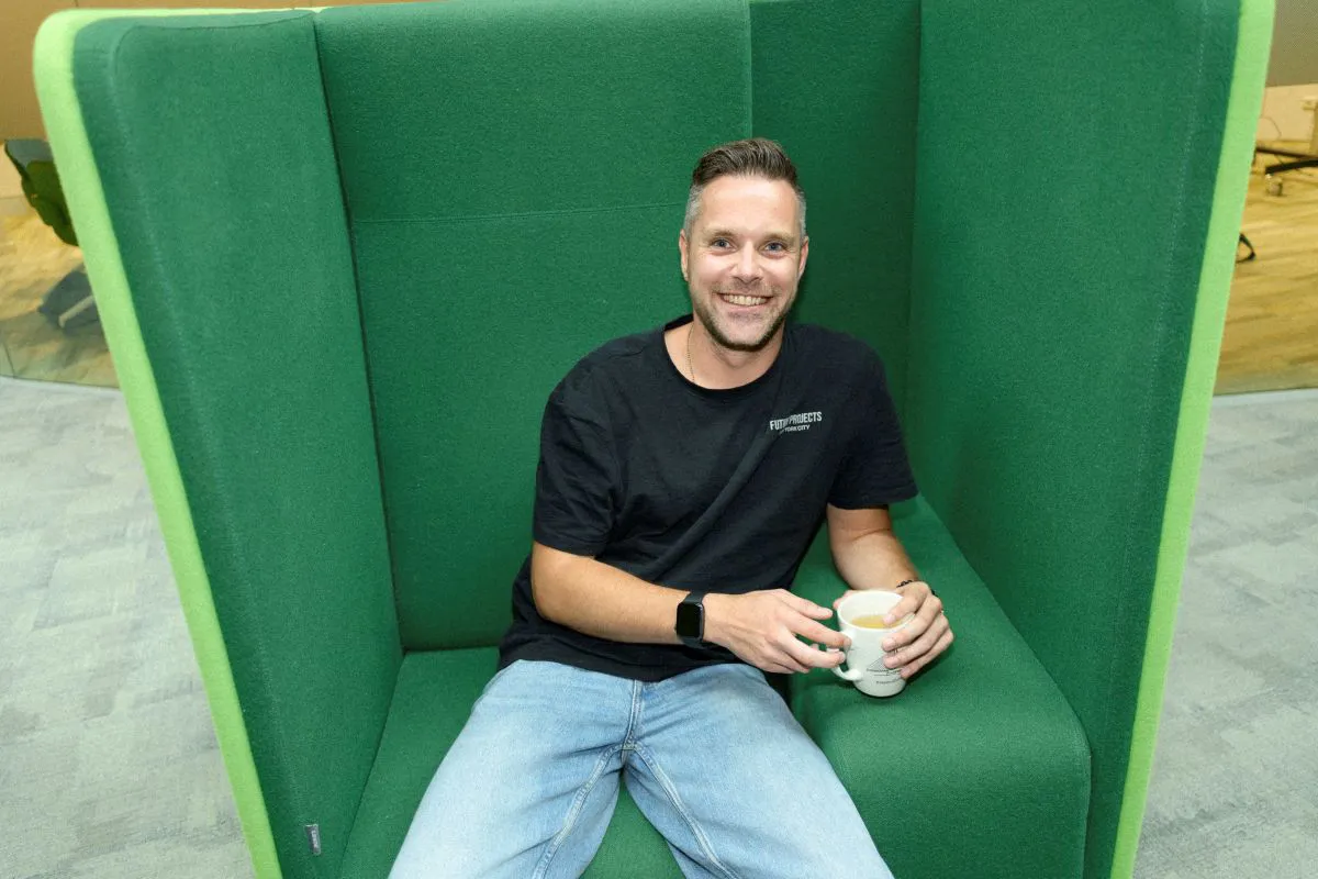 Rowin Visscher Een man zit ontspannen in een comfortabele stoel, met een rustige en tevreden uitstraling. Hij leunt iets achterover met een kop koffie in zijn handen.