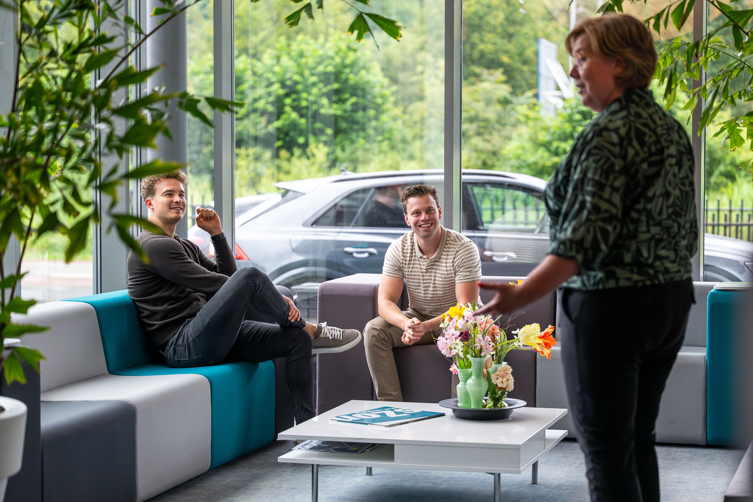 Collega's in ontspannen setting, zittend op een bank bij de entree