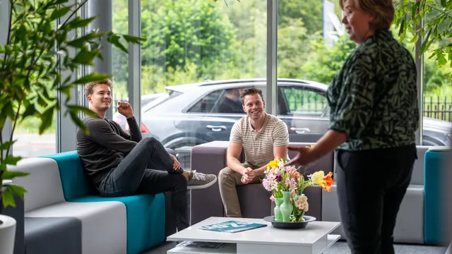 Collega's in ontspannen setting, zittend op een bank bij de entree