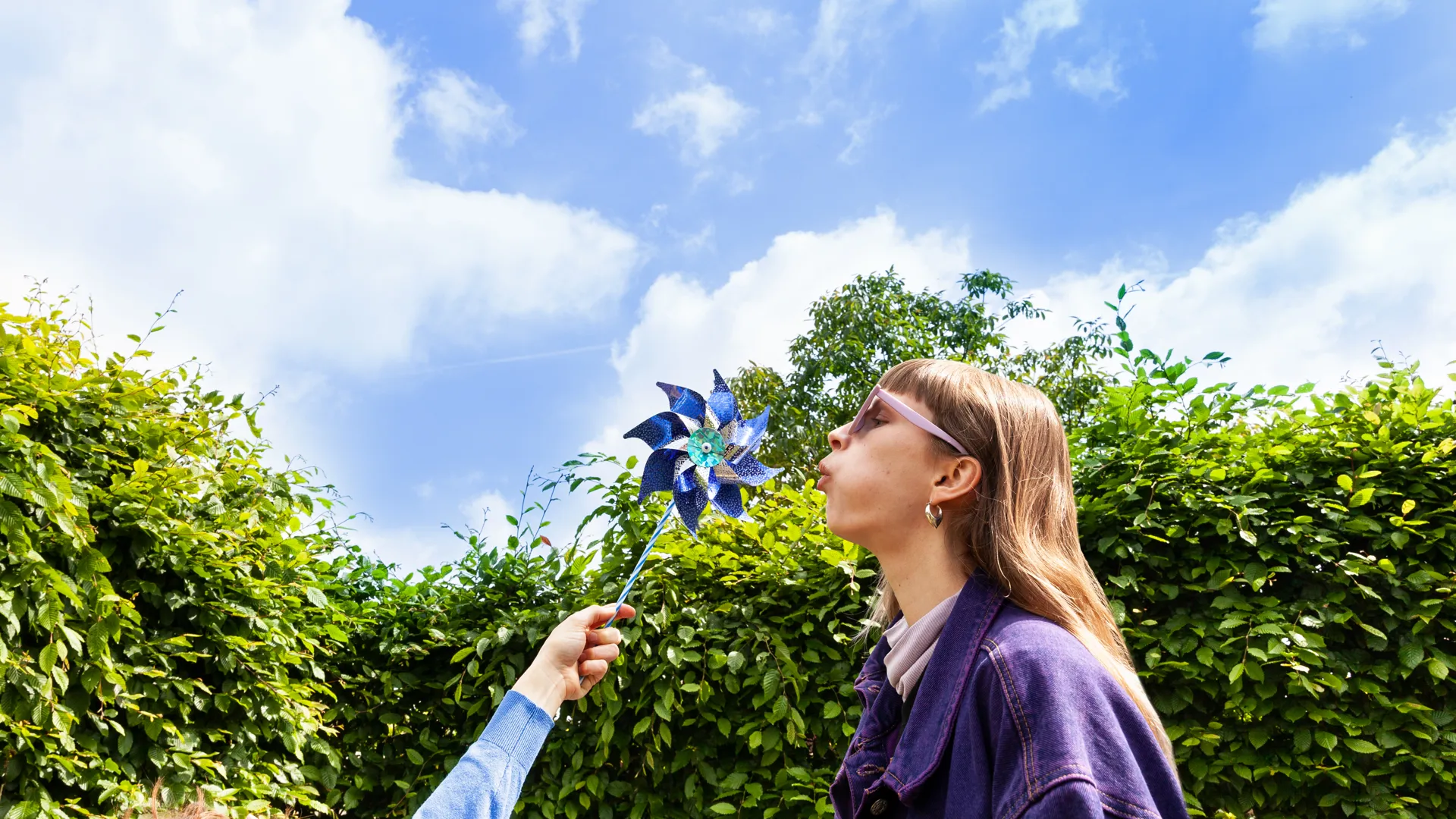 Vrouw en windmolen Vrouw blaast tegen een papieren windmolentje. Ze is opgewekt, net als de windstroom van Greenchoice.