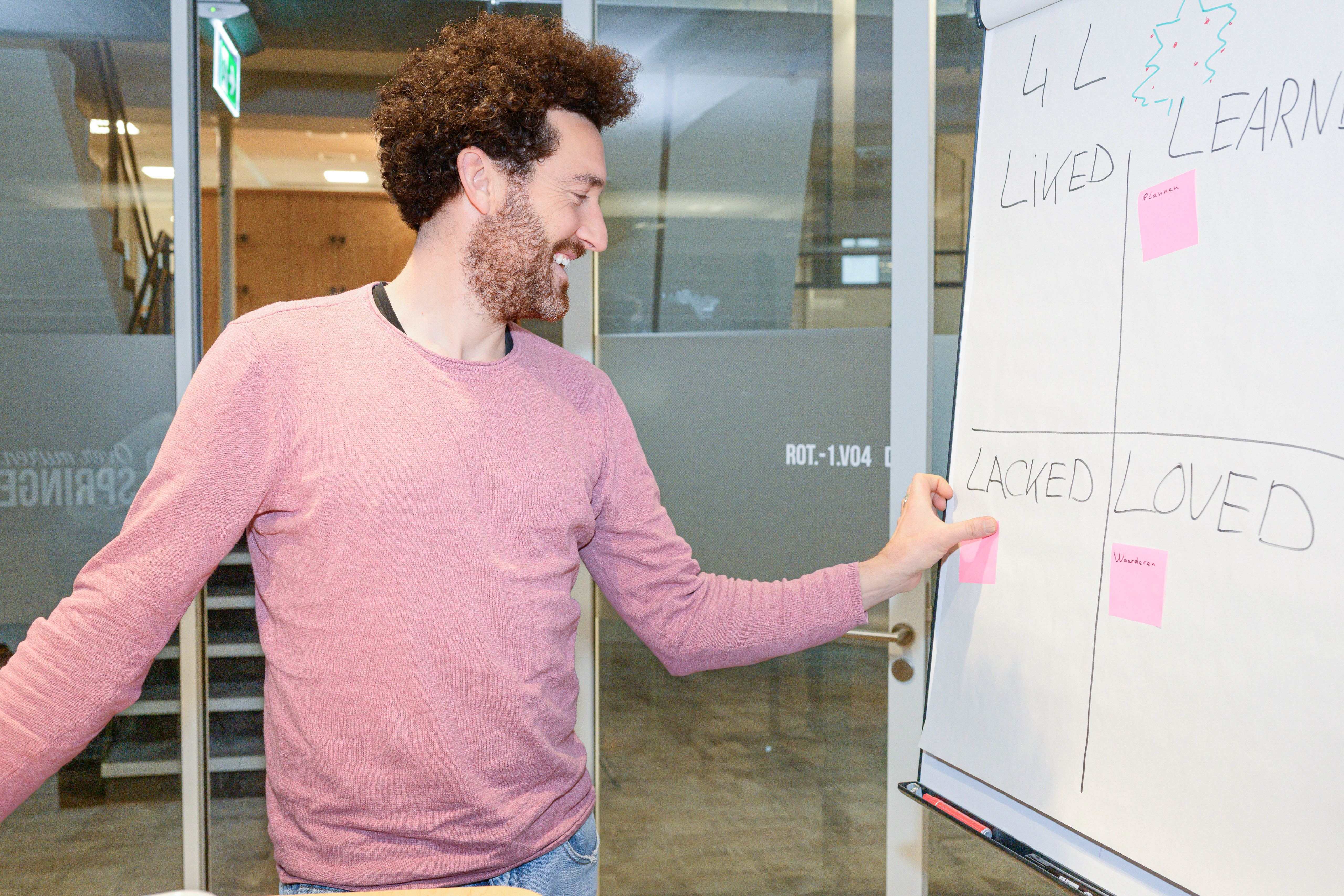 Collega plakt een post-it op een bord tijdens een scrum sessie