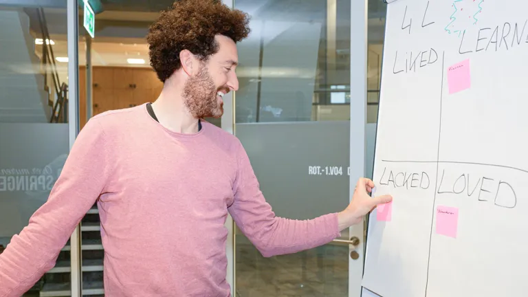 Collega plakt een post-it op een bord tijdens een scrum sessie