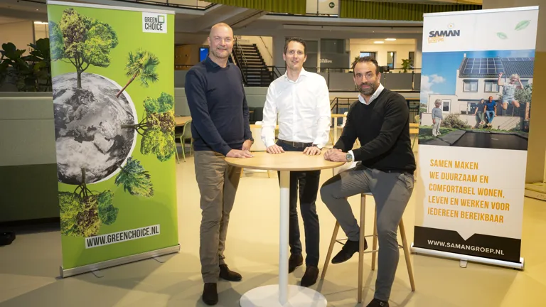 Daniël Lodders en Coen de Ruiter staan samen aan tafel om te vieren dat Saman Groep en Greenchoice een samenwerking aangaan.