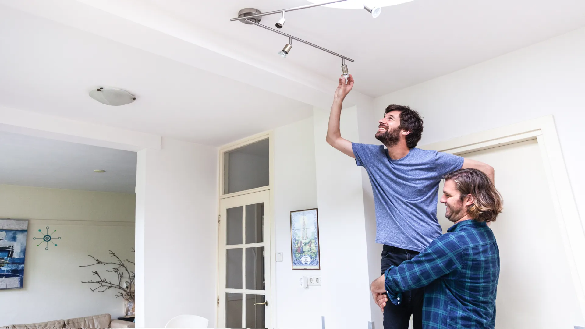 Twee mannen vervangen samen een led-lamp om te besparen op hun stroomrekening