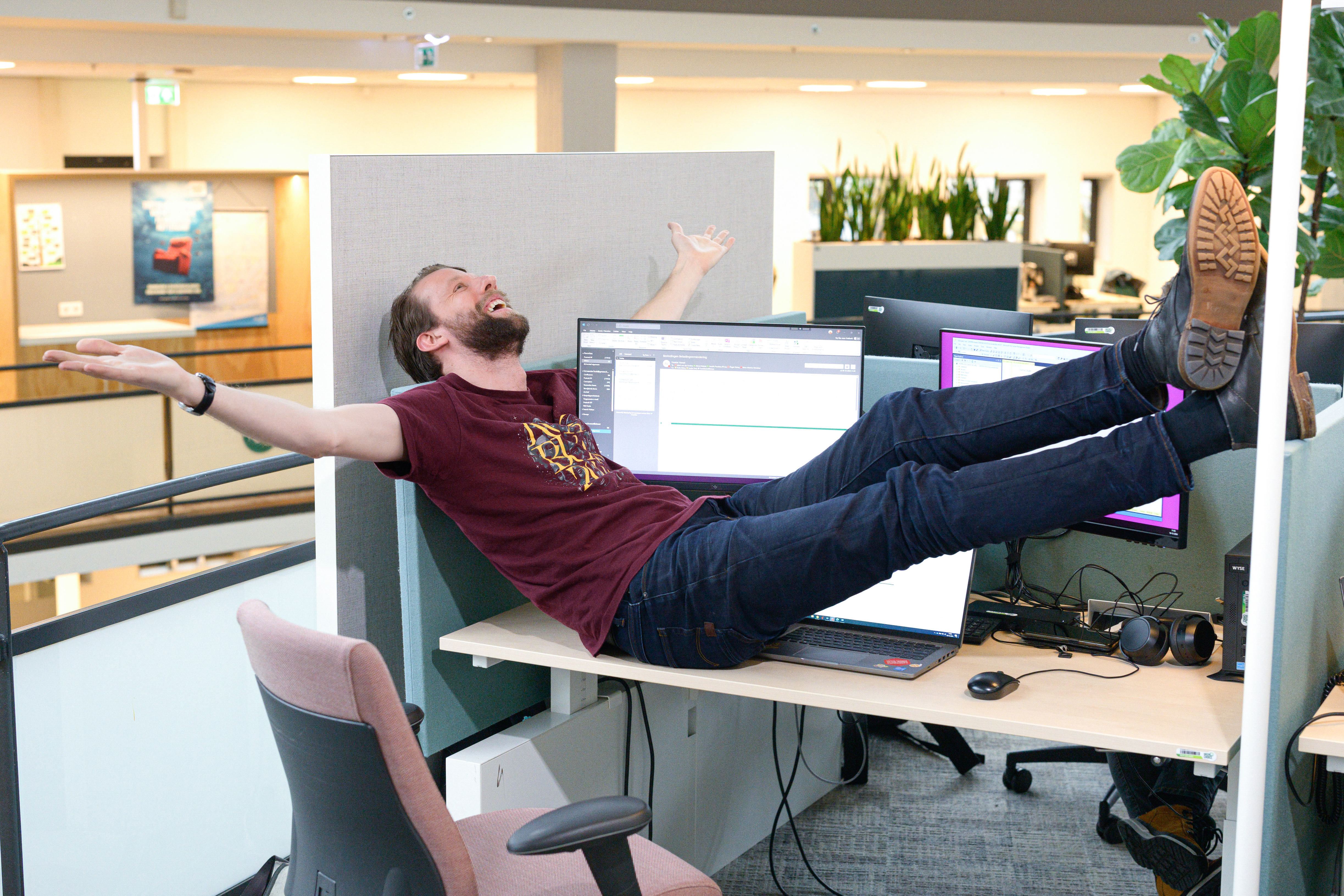 Collega neemt een creatieve koffiepauze: hij ligt languit op het bureau, zichtbaar tevreden