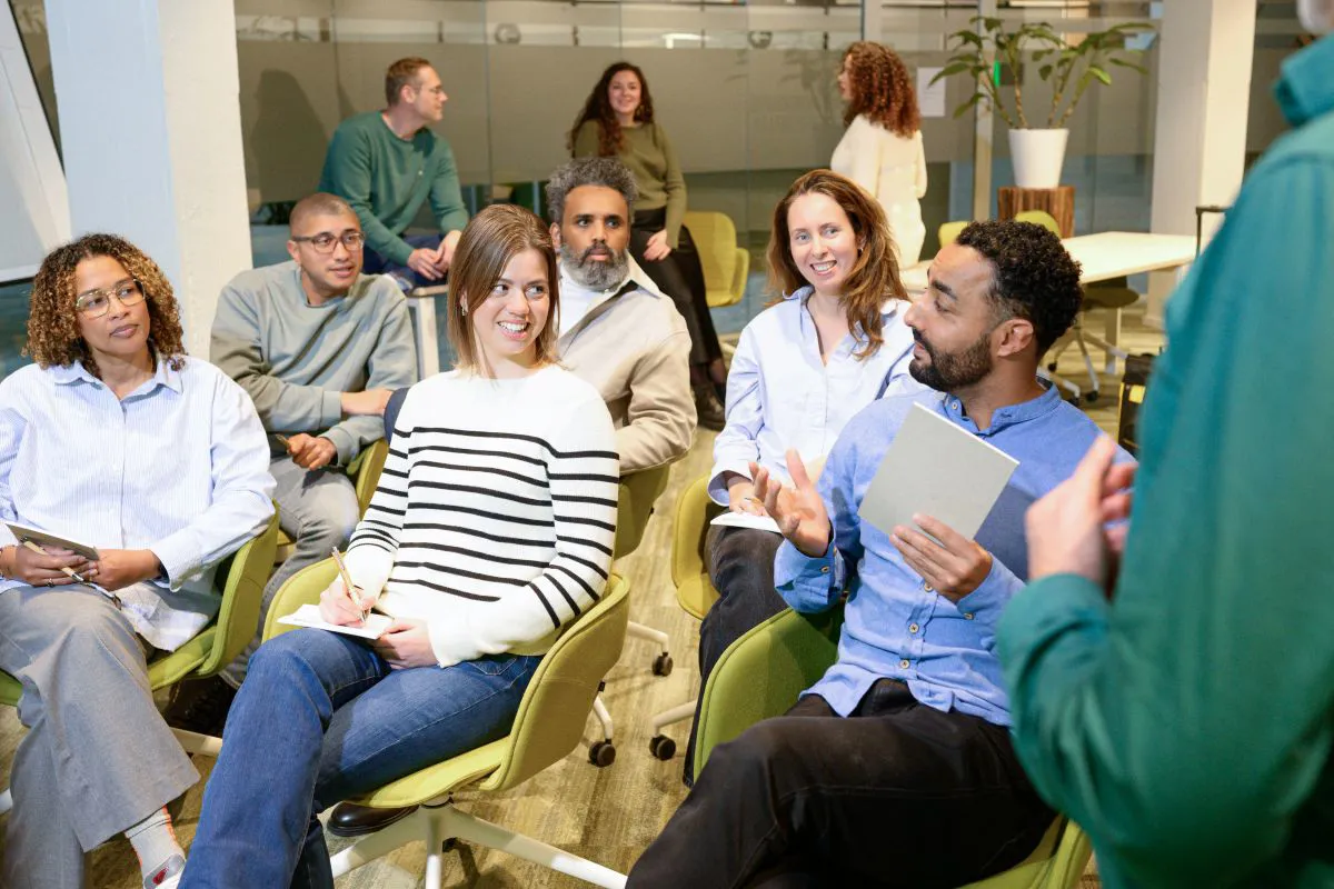 Collega's wisselen ideeën uit tijdens een training, met stoelen in rijen opgesteld als in een theater