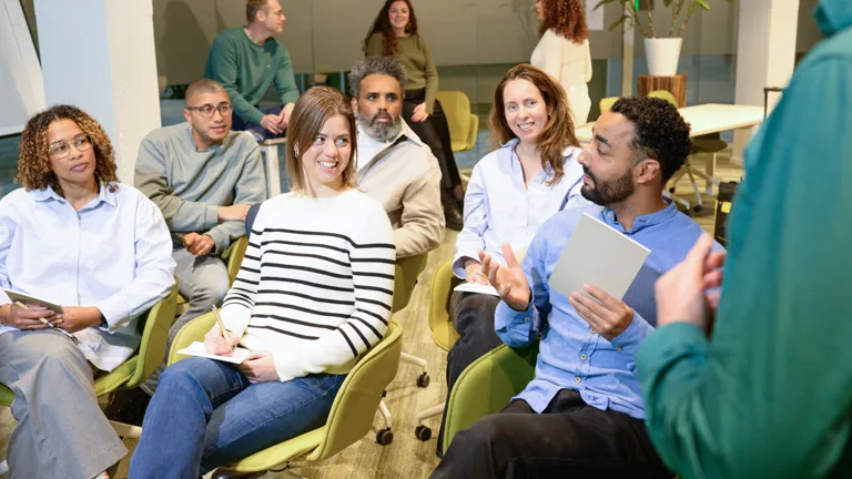Collega's wisselen ideeën uit tijdens een training, met stoelen in rijen opgesteld als in een theater