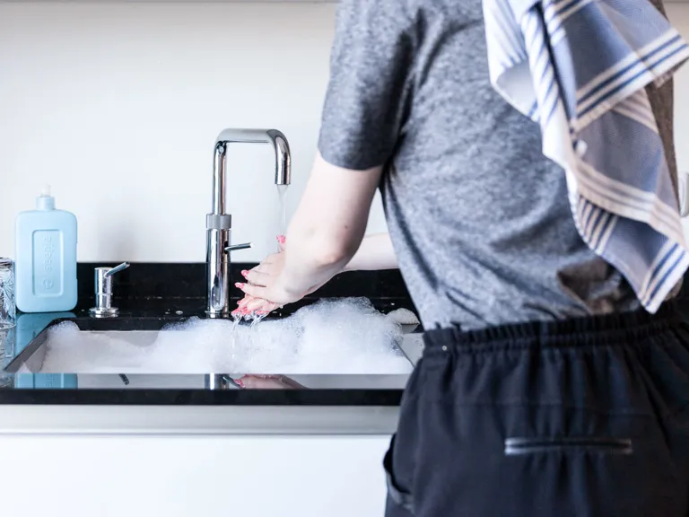 Handen wassen waterverbruik Een persoon wast hun handen in de keuken.