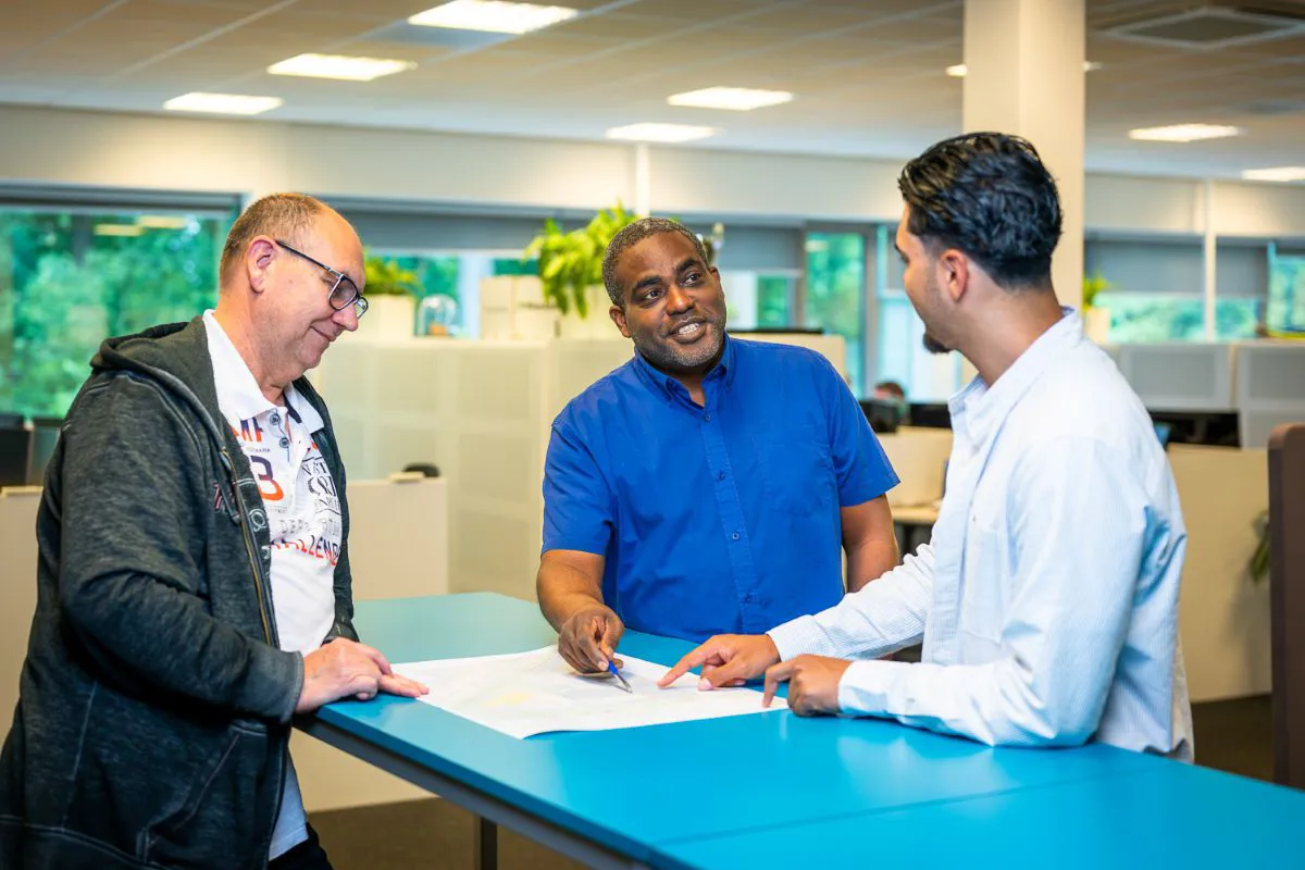 Collega's analyseren een technische tekening en wisselen ideeën uit over het ontwerp