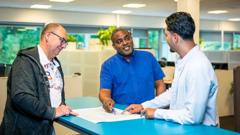 Collega's analyseren een technische tekening en wisselen ideeën uit over het ontwerp